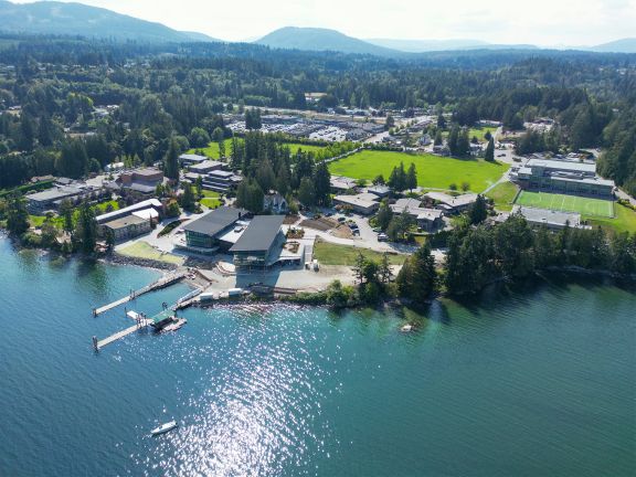 Aerial photo of campus with ocean in front and Mill Bay Centre shops above, at the west edge of campus