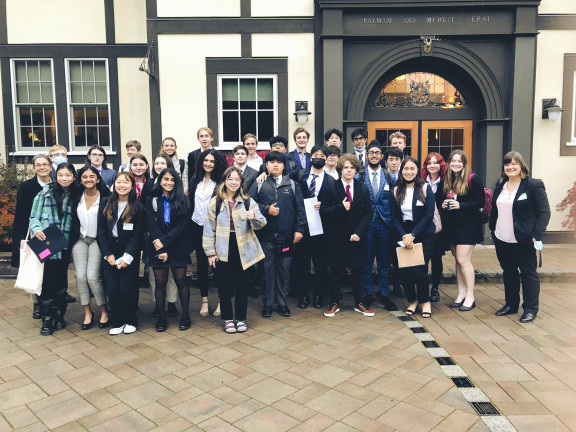 A group of debate students posing for a photo outside a debate hall